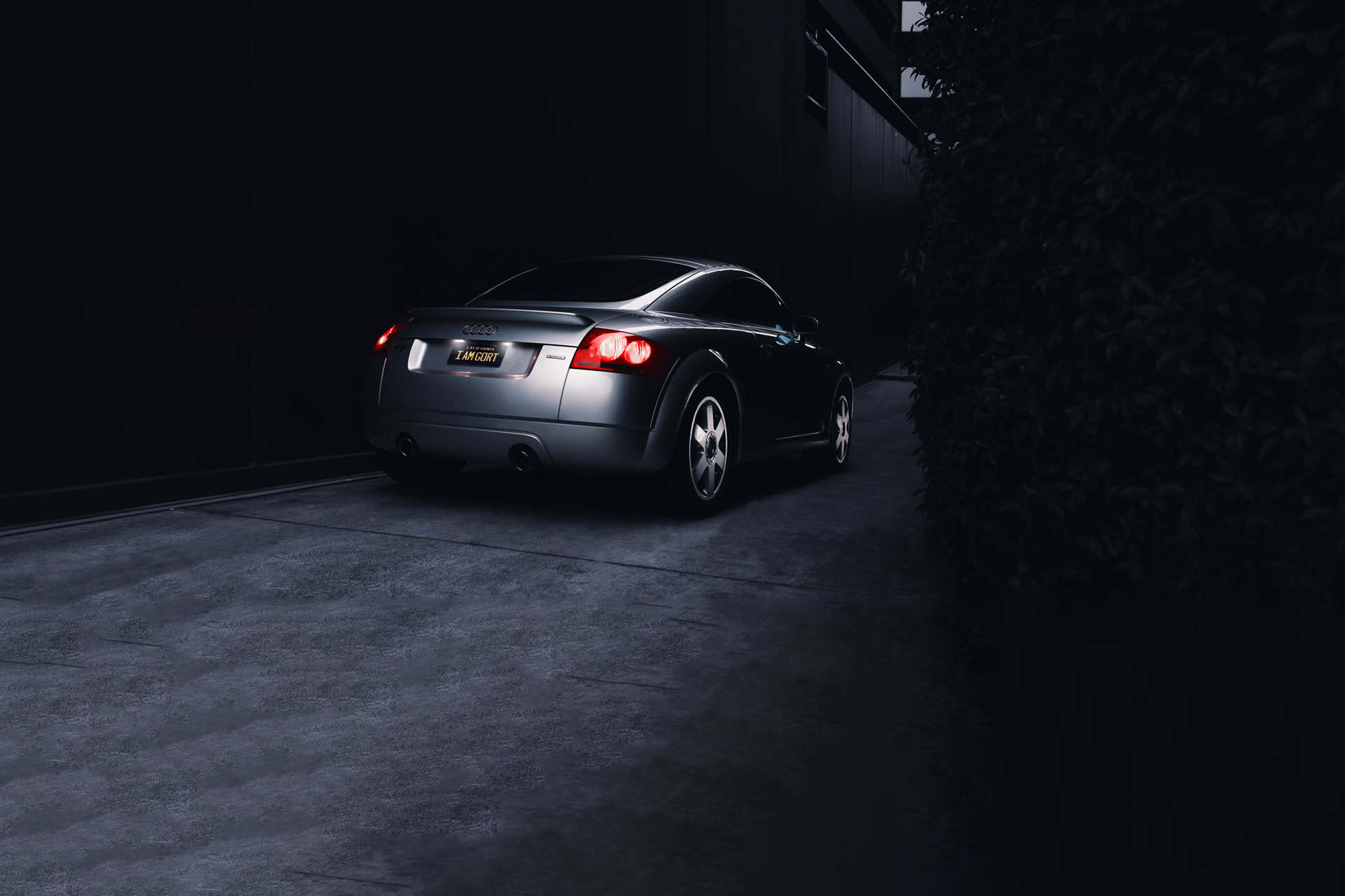 Luxury black Audi coupe parked in a dark driveway at night, illuminated by subtle ambient lighting, showcasing sleek design and sophistication.