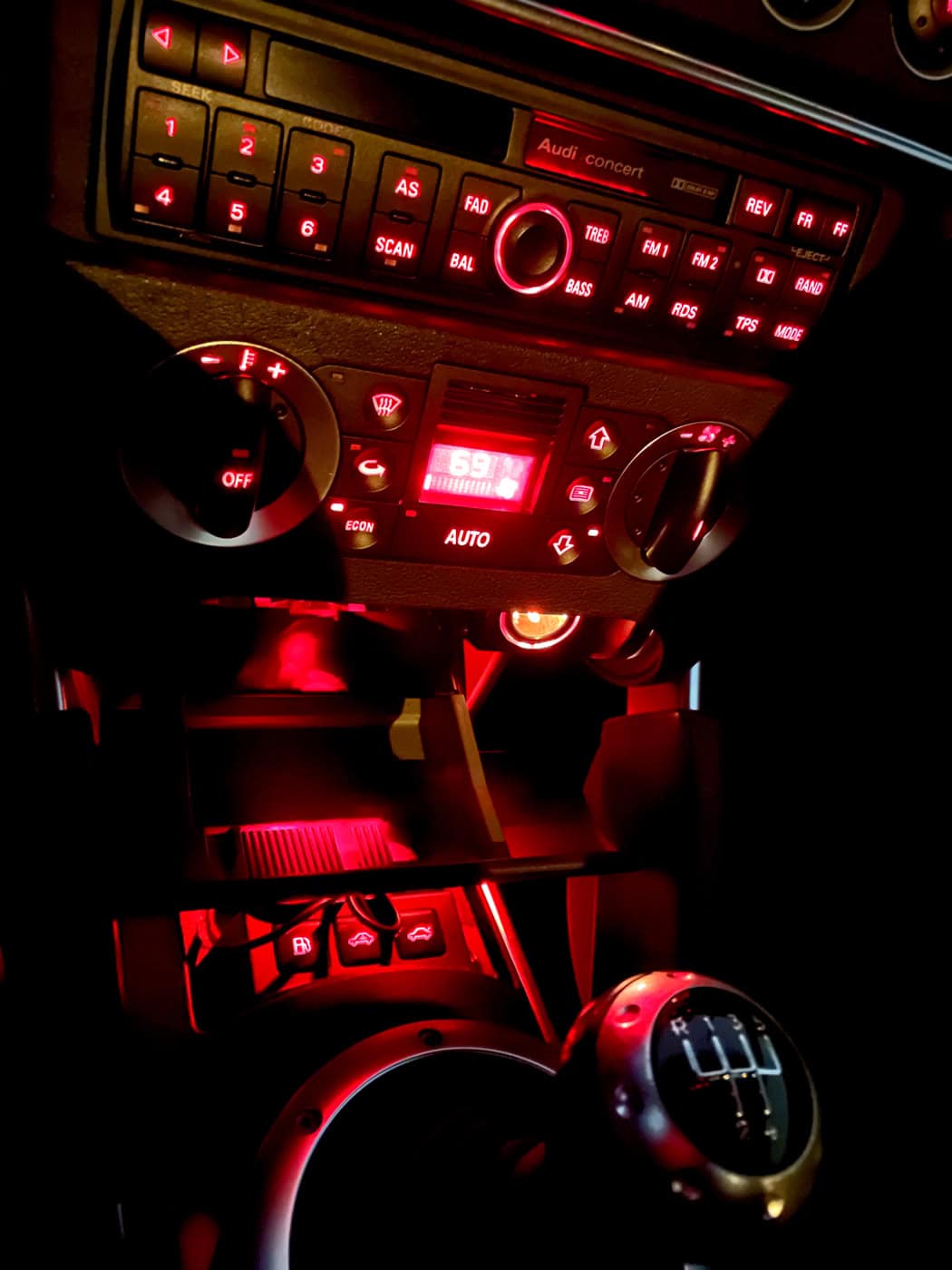 High-performance car dashboard with illuminated controls and digital display, showcasing car interior lighting, climate control, and audio system, emphasizing automotive technology and style.